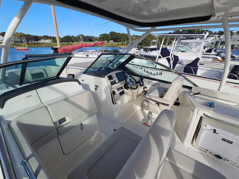 Slide: The Image of 2018 Boston Whaler 270 Vantage boat interior with helm and seating, docked in marina. - 12