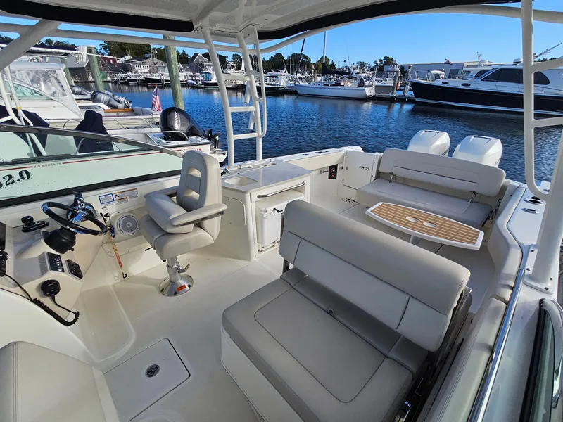 Slide: The Image of 2018 Boston Whaler 270 Vantage boat interior at marina, featuring seating and helm. - 13