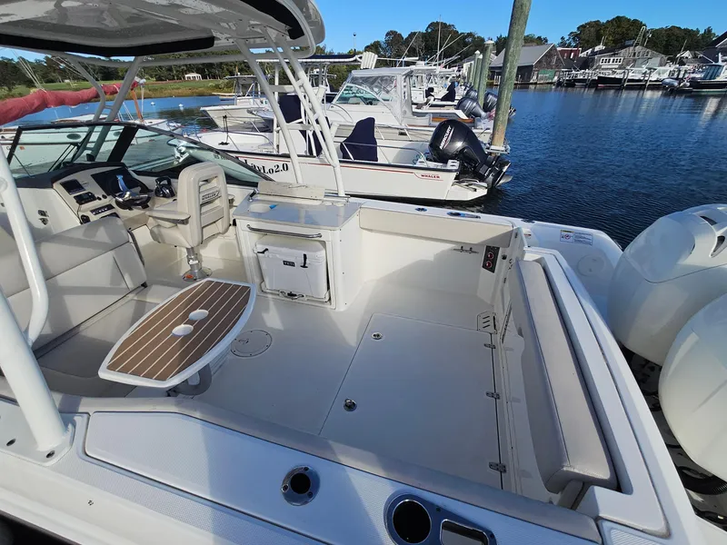 Slide: The Image of 2018 Boston Whaler 270 Vantage boat interior with seating and table, docked at marina. - 20