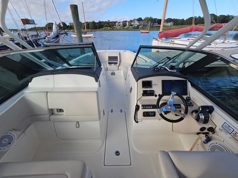 Slide: The Image of 2018 Boston Whaler 270 Vantage boat interior with helm and seating, docked by the water. - 7