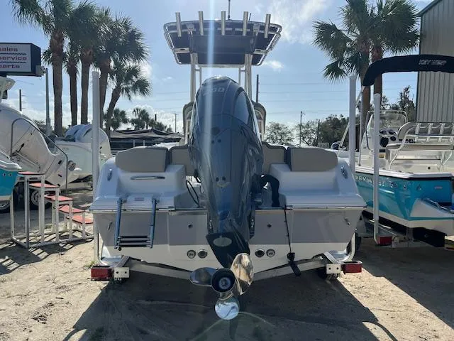 Slide: The Image of 2025 Key West 203 FS boat with outboard motor, parked on a trailer, surrounded by palm trees. - 2
