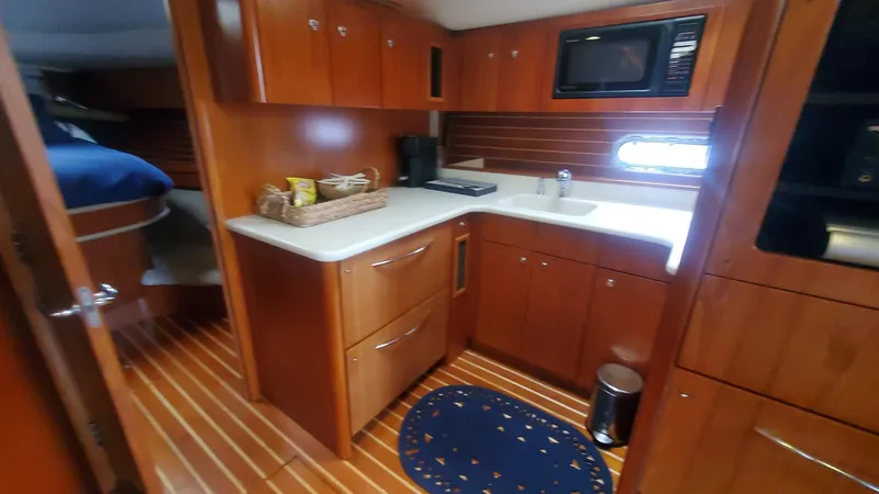 Slide: The Image of Interior of 2001 Tiara Yachts 52 Express Cruiser with wooden cabinetry and compact kitchen. - 13