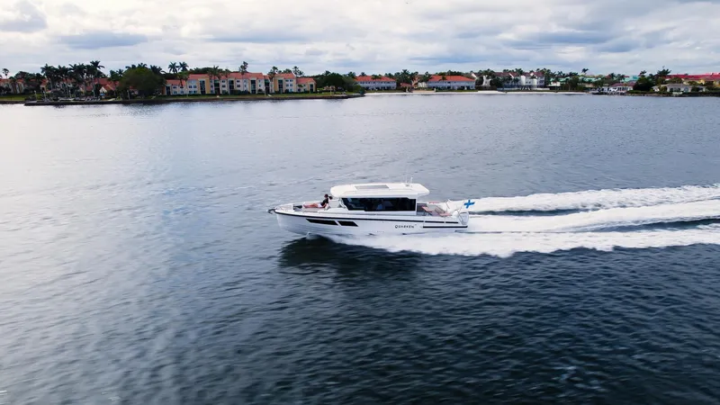 Slide: The Image of 2025 Quarken 35 Cabin boat cruising on a scenic lake with waterfront homes. - 6