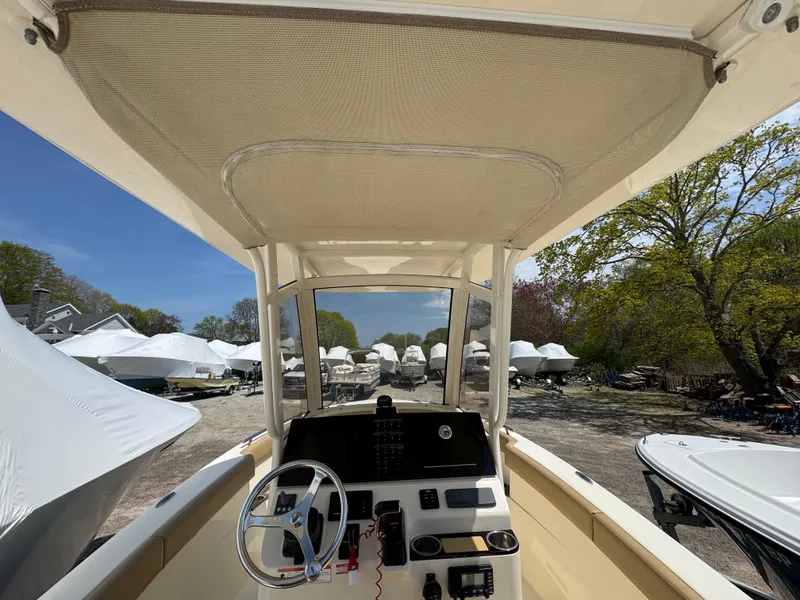 Slide: The Image of 2019 Scout 235 XSF boat interior with steering wheel, parked among covered boats. - 10