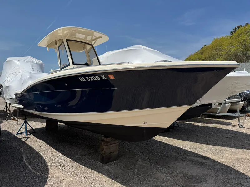 Slide: The Image of 2019 Scout 235 XSF boat on display outdoors, blue hull, white top, sunny day. - 2