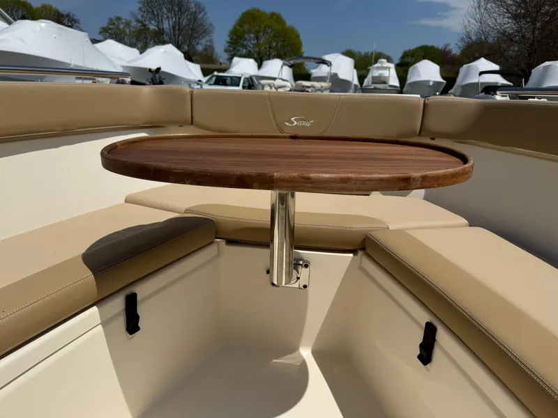 Slide: The Image of 2019 Scout 235 XSF boat interior with round wooden table and beige seating. - 28