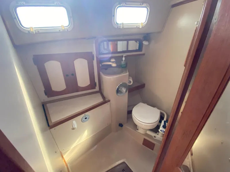 Slide: The Image of 1991 Newport 31 boat bathroom with toilet, sink, and storage cabinets. - 11