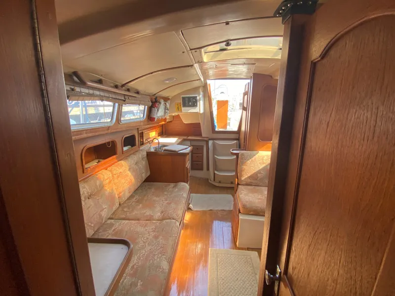 Slide: The Image of Interior of a 1991 Newport 31 sailboat with cozy seating and wooden finishes. - 13