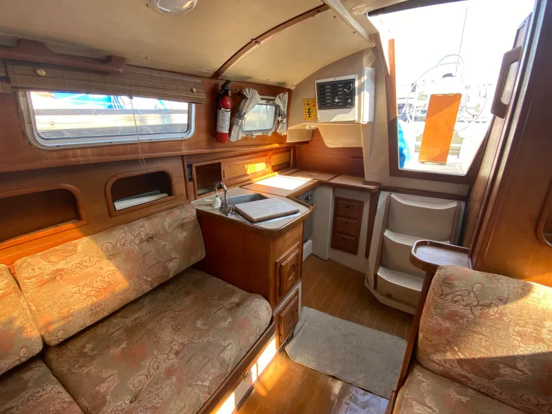 Slide: The Image of Interior of a 1991 Newport 31 sailboat with cozy seating and compact kitchen area. - 14