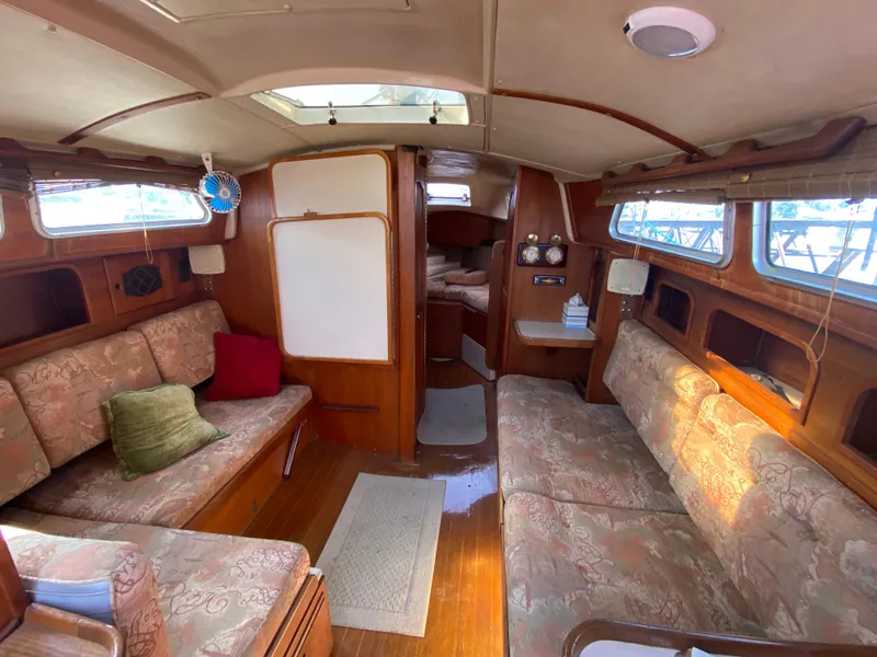 Slide: The Image of 1991 Newport 31 sailboat interior with cozy seating and wooden finishes. - 7