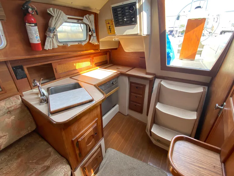 Slide: The Image of Cozy 1991 Newport 31 yacht interior with kitchenette, sink, and wooden cabinetry. - 8