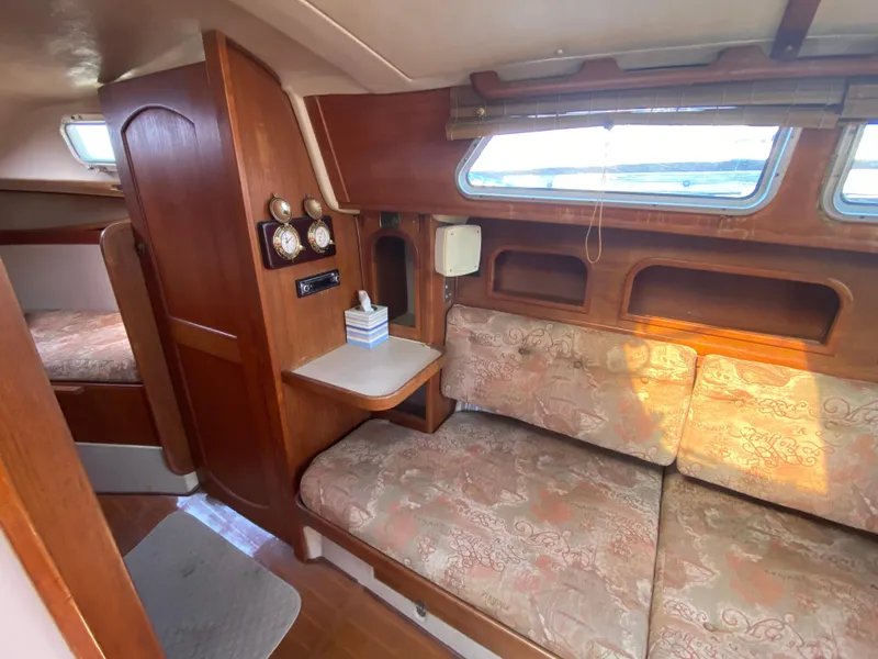 Slide: The Image of Cozy interior of 1991 Newport 31 sailboat with wood paneling and cushioned seating. - 9