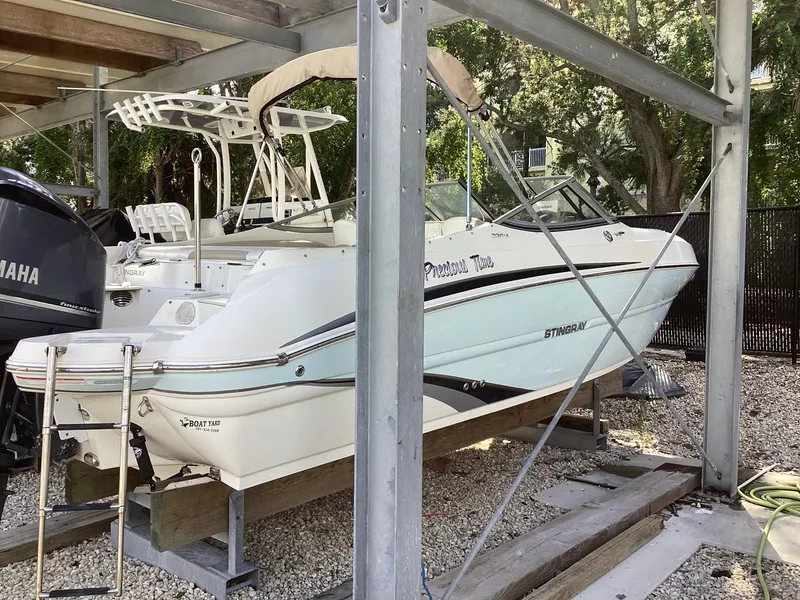 Slide: The Image of 2017 Stingray 234 LR boat on a lift, white exterior, parked outdoors. - 0