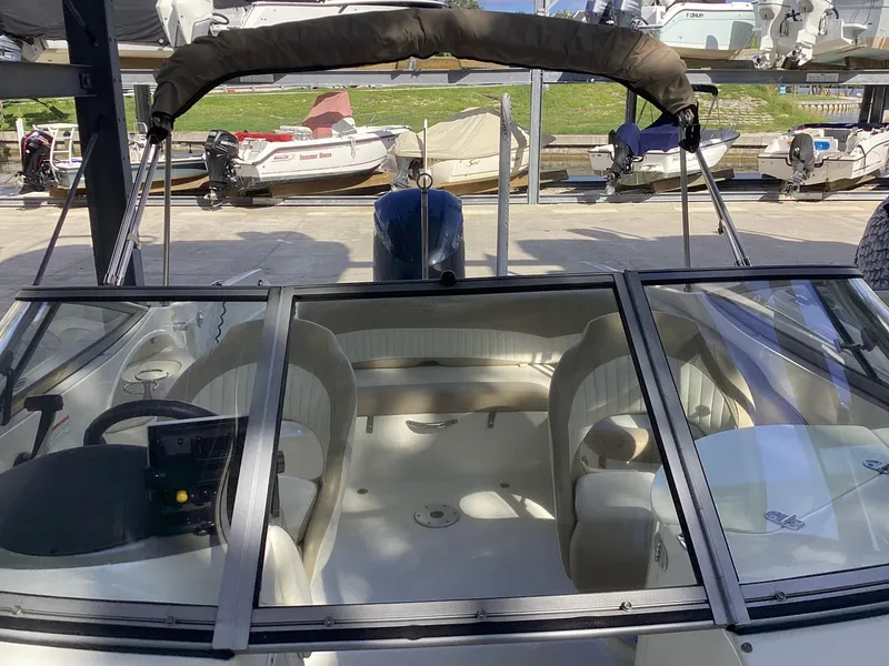 Slide: The Image of 2017 Stingray 234 LR boat interior with seating and dashboard, docked at marina. - 10