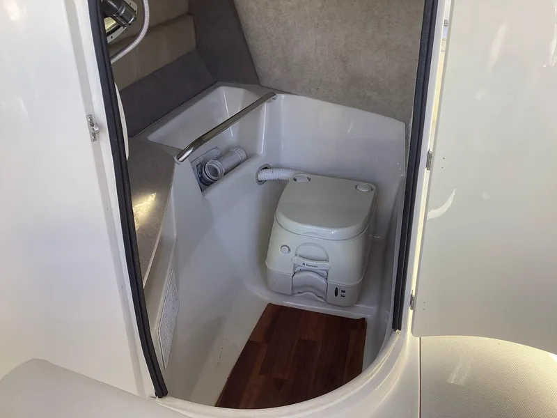 Slide: The Image of 2017 Stingray 234 LR boat interior with compact toilet and seating area. - 24