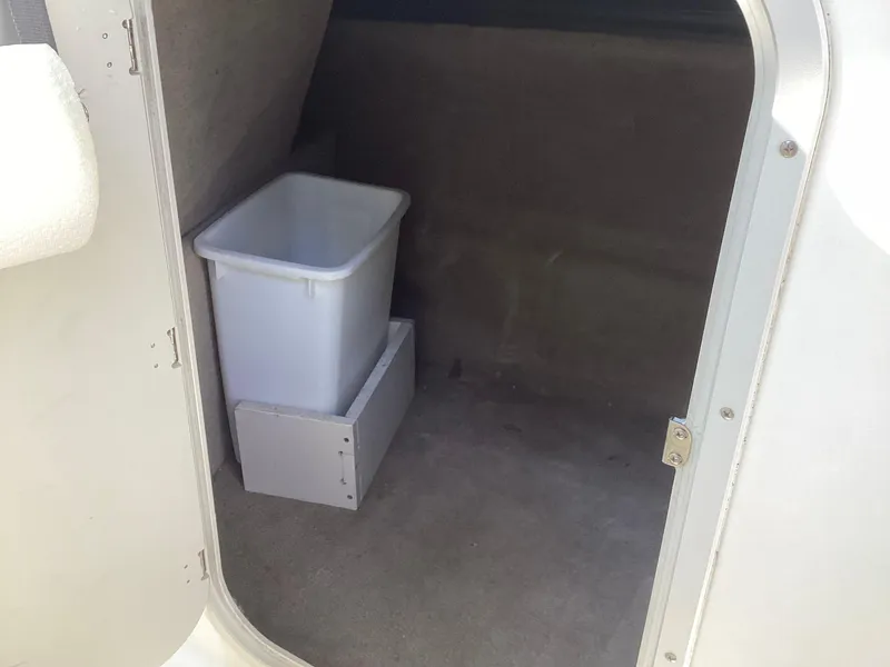 Slide: The Image of Interior storage compartment of 2017 Stingray 234 LR boat with a white bin. - 28