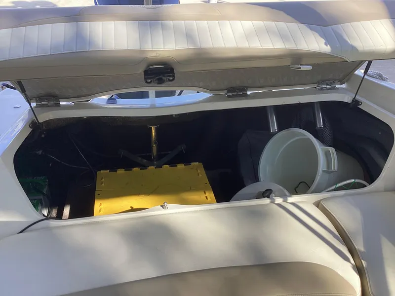 Slide: The Image of Open storage compartment in 2017 Stingray 234 LR boat with yellow box and white bucket. - 43