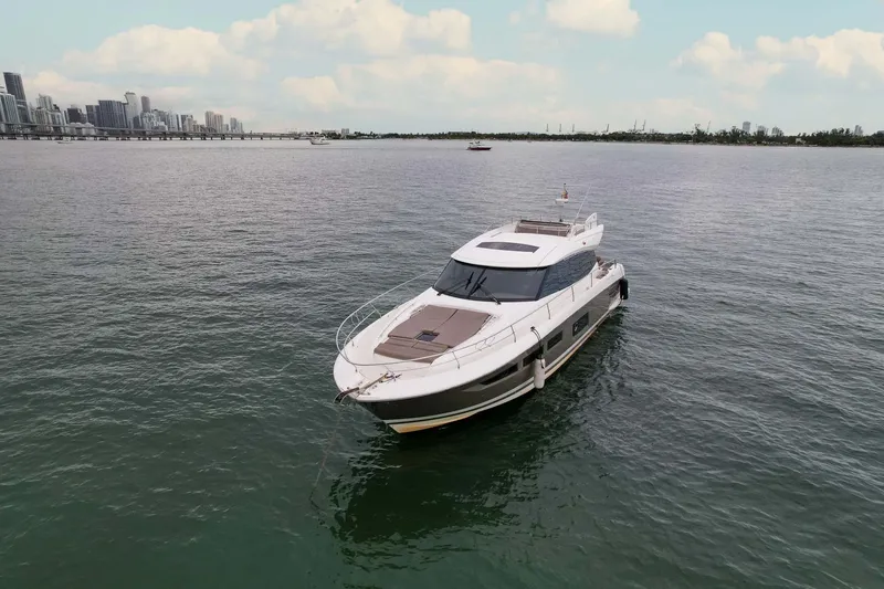 Slide: The Image of Luxury 2015 Prestige 520 yacht cruising on calm waters with city skyline backdrop. - 31