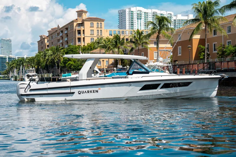 The Image of 2025 Quarken 35 Sport Tourer boat cruising near waterfront buildings and palm trees. - 1