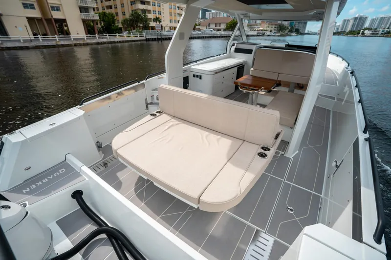 Slide: The Image of 2025 Quarken 35 Sport Tourer boat interior with seating and table on a calm waterway. - 13
