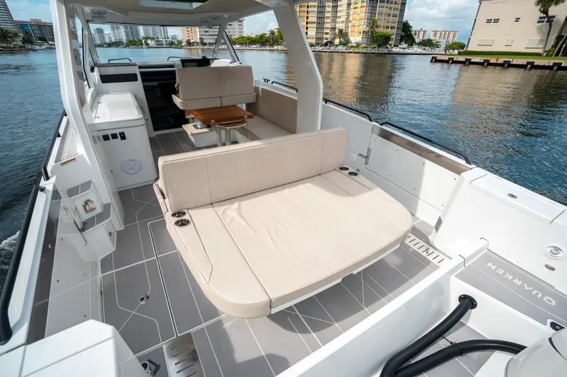 Slide: The Image of 2025 Quarken 35 Sport Tourer boat interior with seating and table on a calm waterway. - 12