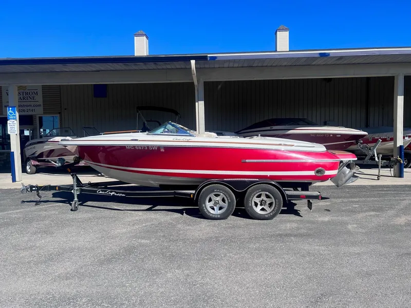 Slide: The Image of 2005 Chris-Craft Speedster boat in red on a trailer, parked outdoors. - 0