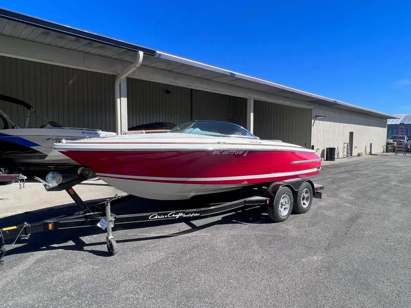 Slide: The Image of 2005 Chris-Craft Speedster boat on trailer, red and white, parked outdoors. - 1
