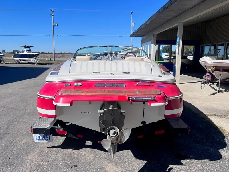 Slide: The Image of 2005 Chris-Craft Speedster boat, red and white, parked outdoors near a building. - 5