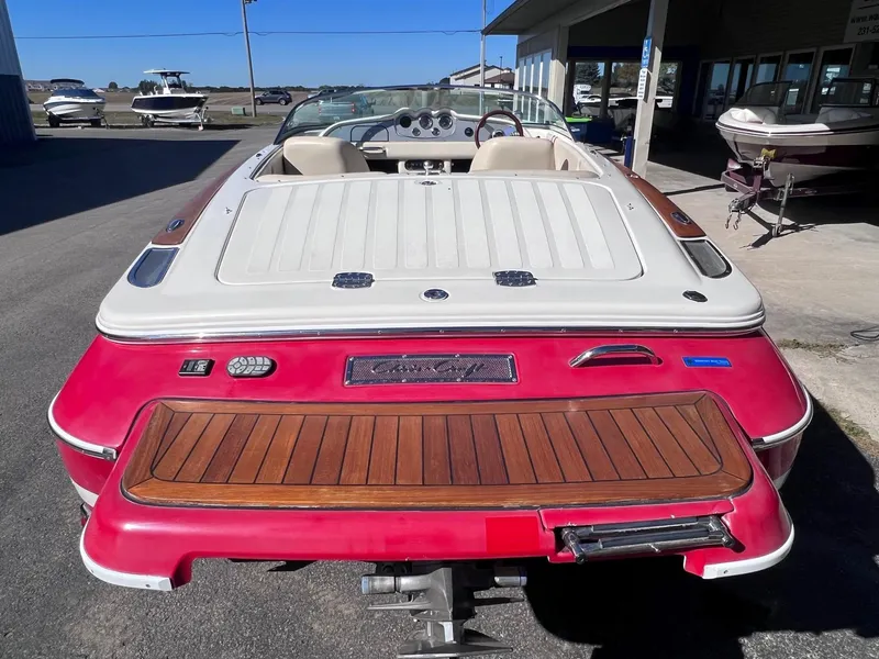 Slide: The Image of 2005 Chris-Craft Speedster boat with red and white exterior, wooden deck, parked outdoors. - 6