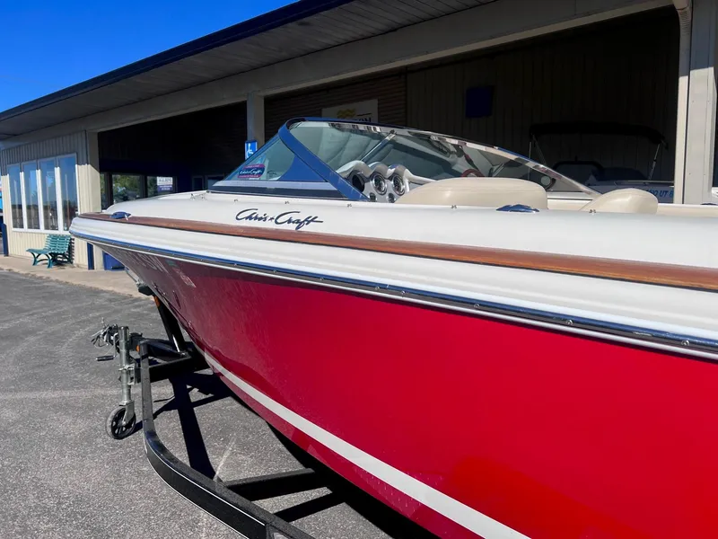 Slide: The Image of 2005 Chris-Craft Speedster boat with red hull on trailer, parked outdoors. - 7