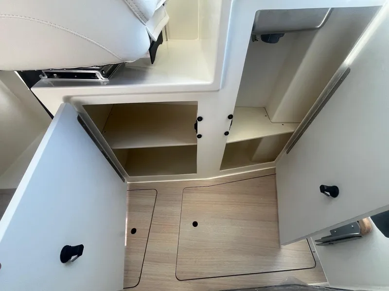 Slide: The Image of 2025 Bayliner Trophy T25 Pilothouse interior storage compartments open. - 19