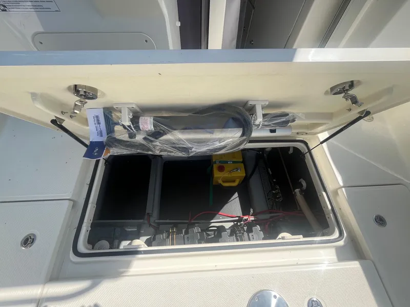 Slide: The Image of Open hatch of 2025 Bayliner Trophy T25 Pilothouse showing storage compartment and equipment. - 30