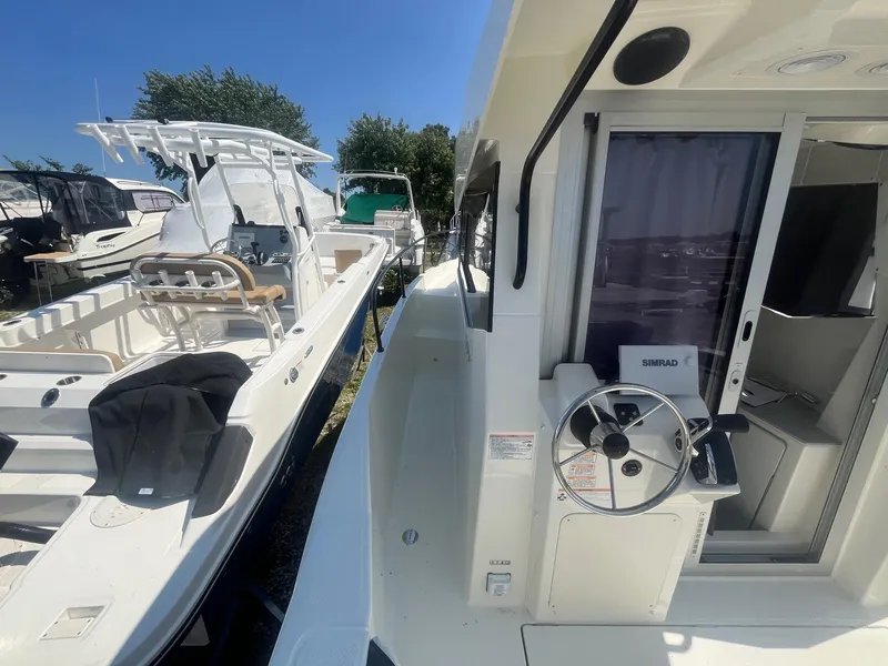 Slide: The Image of 2025 Bayliner Trophy T25 Pilothouse boat docked beside another vessel. - 36