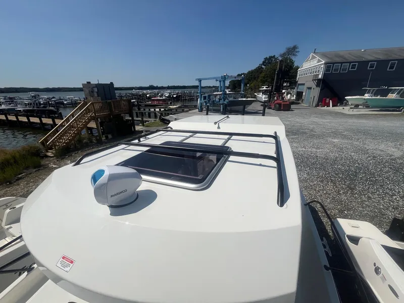 Slide: The Image of 2025 Bayliner Trophy T25 Pilothouse boat docked at marina under clear blue sky. - 38