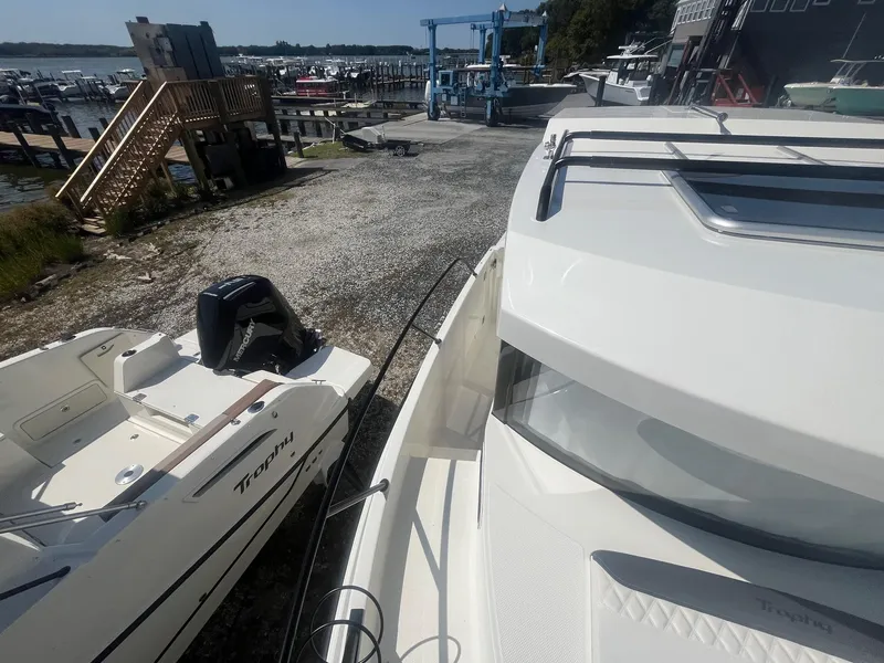 Slide: The Image of 2025 Bayliner Trophy T25 Pilothouse boat docked at a marina with other vessels. - 41