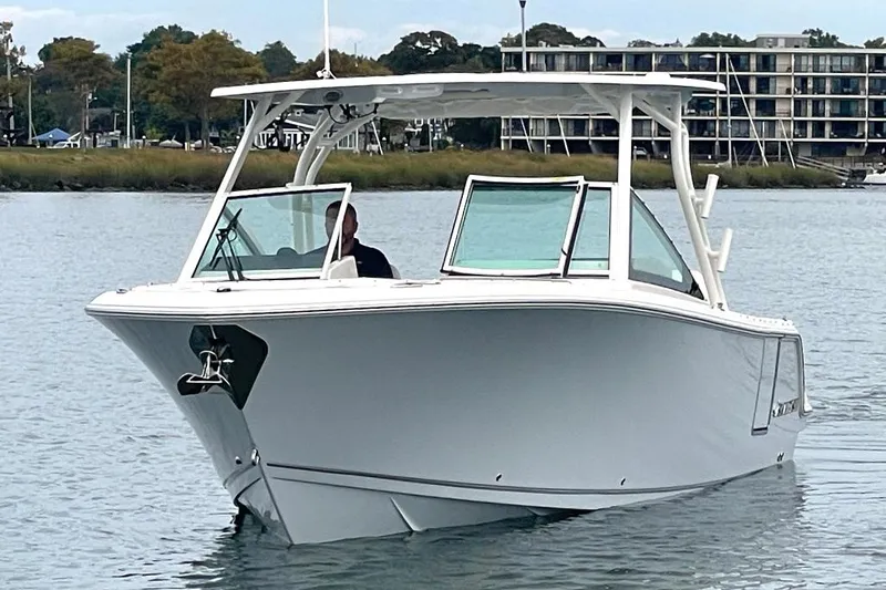 Slide: The Image of 2025 Sailfish 276 DC boat cruising on calm water near shoreline buildings. - 4