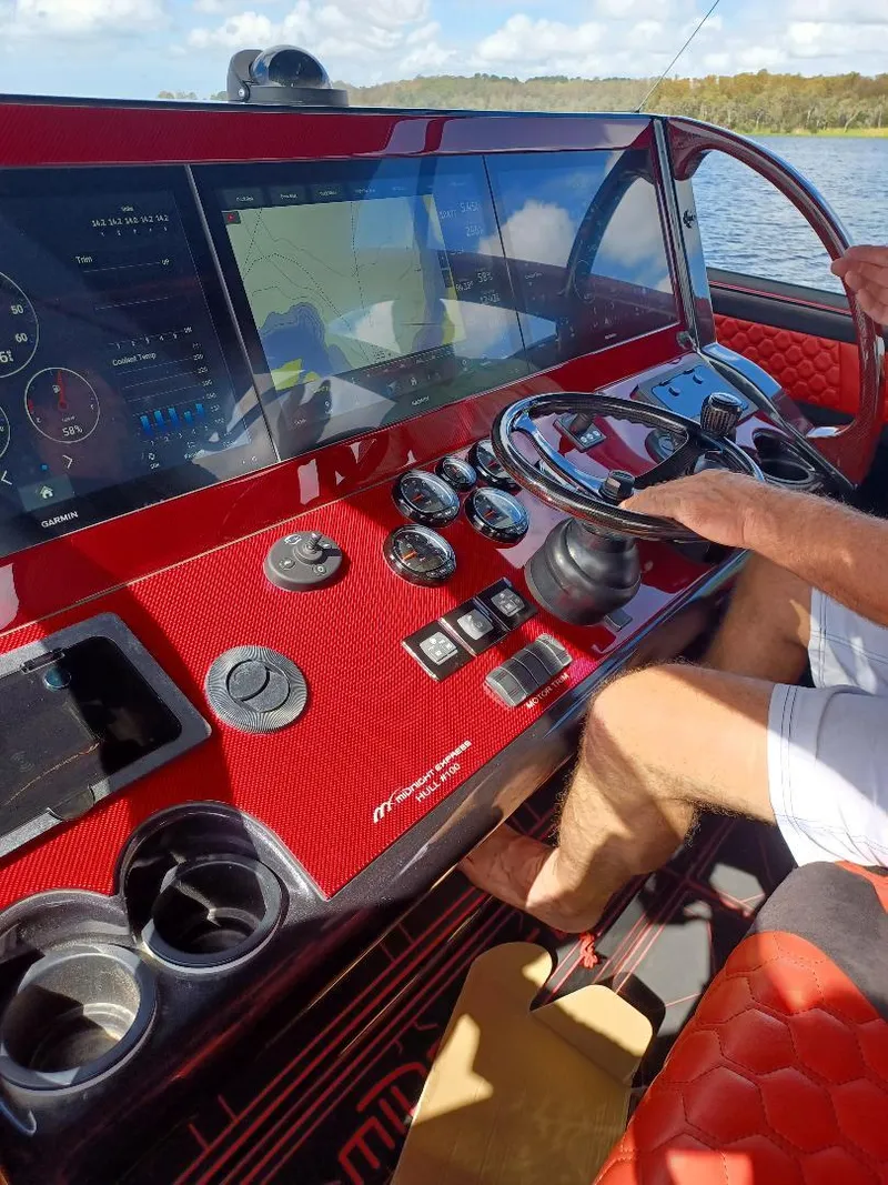 Slide: The Image of 2022 Midnight Express 43' Solstice boat dashboard with red interior and advanced navigation system. - 10