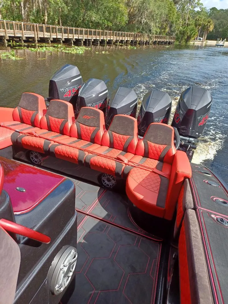 Slide: The Image of 2022 Midnight Express 43' Solstice boat with red seating and multiple outboard engines on a river. - 5