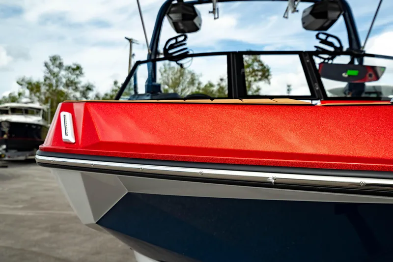 Slide: The Image of 2025 Nautique Super Air Nautique GS20 boat, vibrant red and blue design, docked outdoors. - 12
