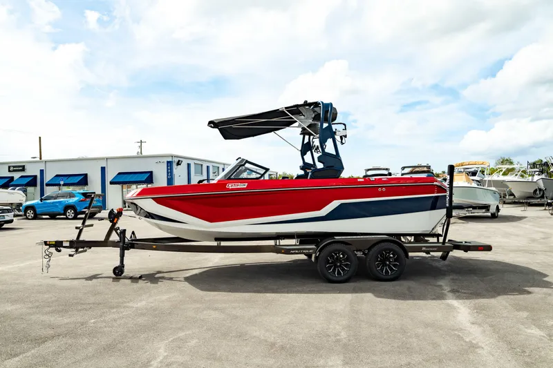Slide: The Image of 2025 Nautique Super Air Nautique GS20 boat on trailer, red and white design. - 9