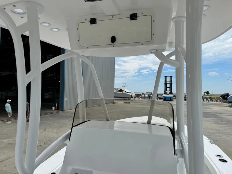 Slide: The Image of 2025 BlackJack 256 Coastal boat interior at marina, showcasing helm and T-top structure. - 22