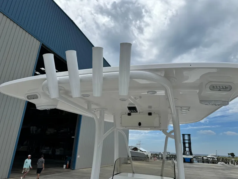 Slide: The Image of 2025 BlackJack 256 Coastal boat with T-top and rod holders near a marina. - 28