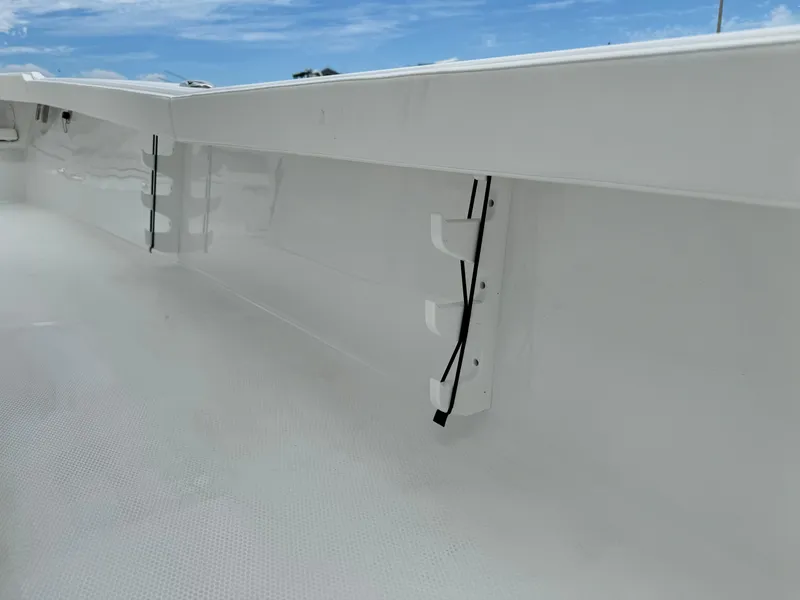 Slide: The Image of 2025 BlackJack 256 Coastal boat interior with rod holders, white finish, and clear blue sky. - 29