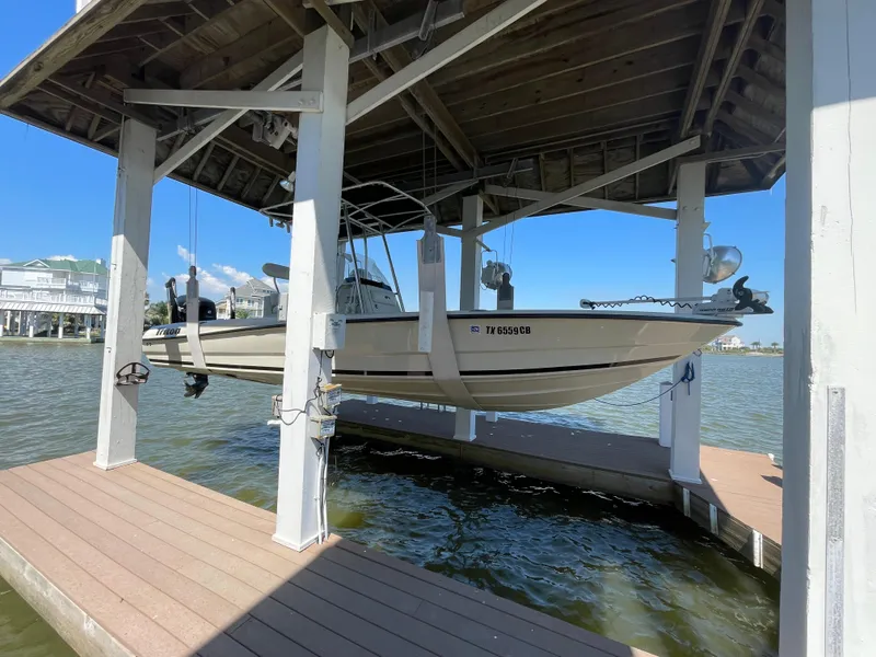 Slide: The Image of 2014 Triton 240 LTS Pro boat suspended in a dock lift over water. - 0