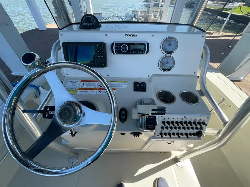 Slide: The Image of 2014 Triton 240 LTS Pro boat console with steering wheel, gauges, and controls. - 10