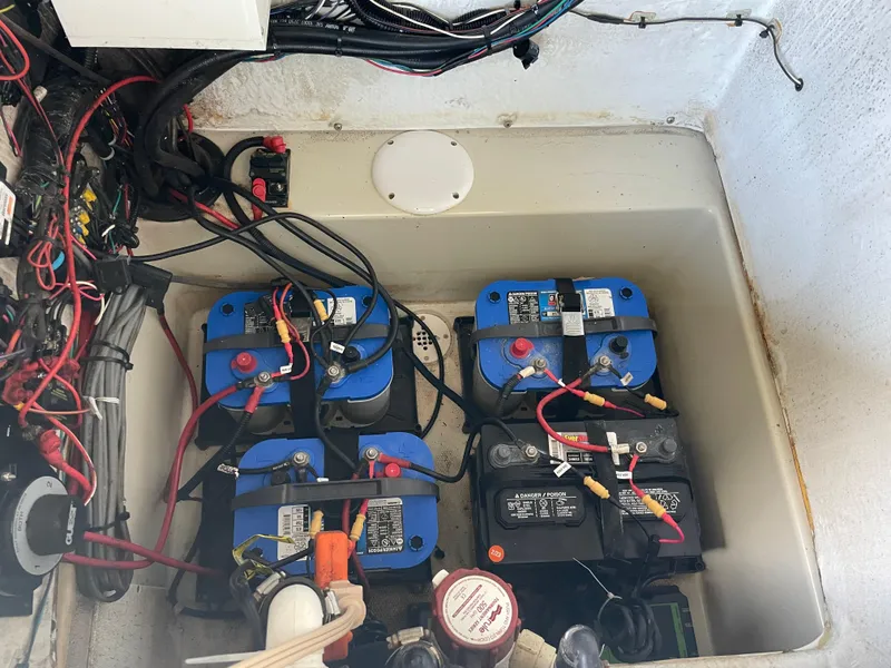 Slide: The Image of 2014 Triton 240 LTS Pro boat battery compartment with wiring and four batteries. - 13