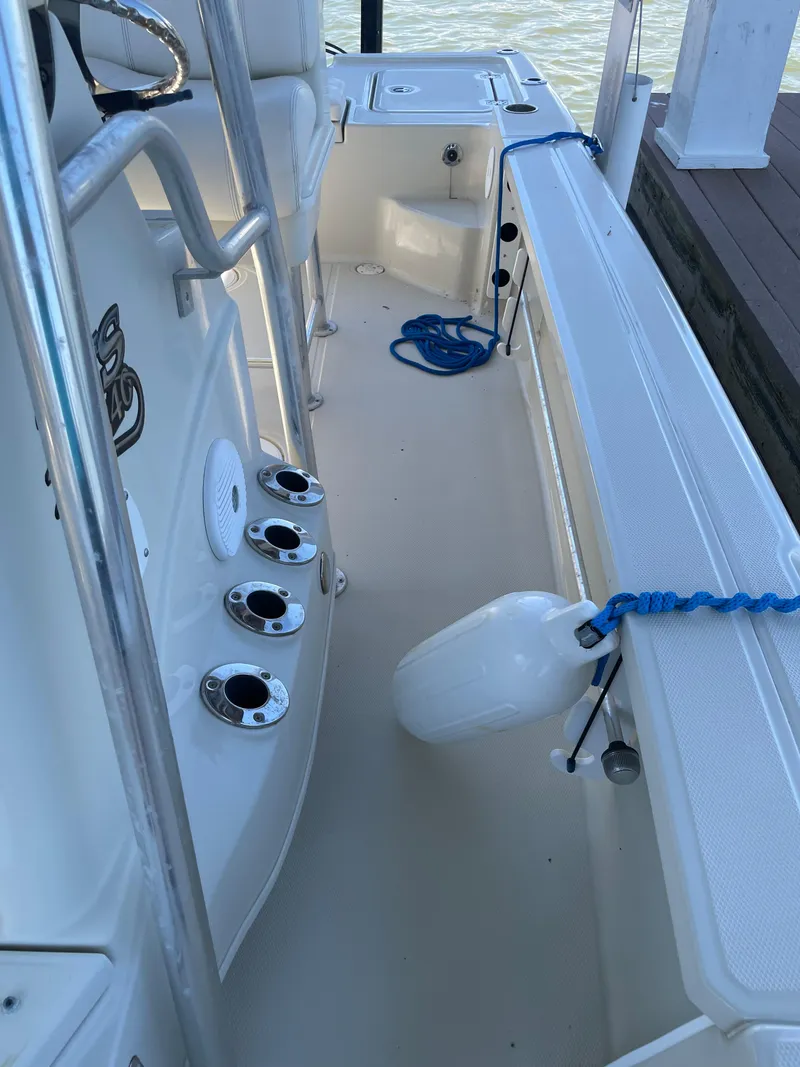 Slide: The Image of 2014 Triton 240 LTS Pro boat interior with rod holders and docked fender. - 14