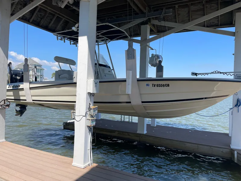 Slide: The Image of 2014 Triton 240 LTS Pro boat suspended in a dock lift over water. - 2
