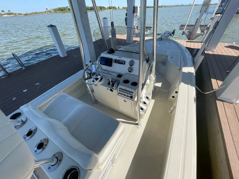 Slide: The Image of 2014 Triton 240 LTS Pro boat interior with steering console, docked by the water. - 23