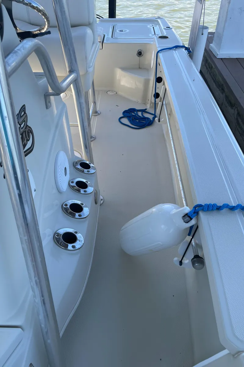 Slide: The Image of 2014 Triton 240 LTS Pro boat interior with fishing rod holders and dock fender. - 27